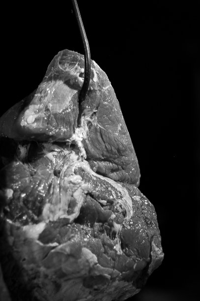 近距离照片，新鲜牛肉挂在金属钩子上展示在肉类市场。图片下载