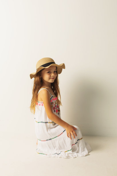 金发女孩在白色背景的白色连衣裙和帽子的工作室。风格图片下载