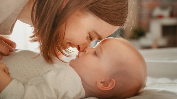 一个快乐的母亲和一个可爱的新生儿玩耍的特写。妈妈和蹒跚学步的孩子亲近，揉肚子，亲吻鼻子。童年，新生活，母亲的概念。图片下载