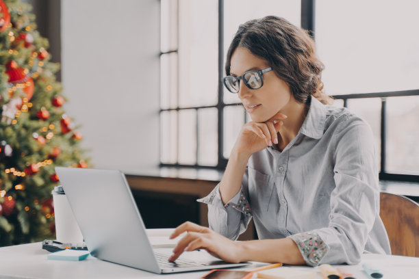 集中的欧洲商业妇女在办公室的电脑上为圣诞节装饰图片下载