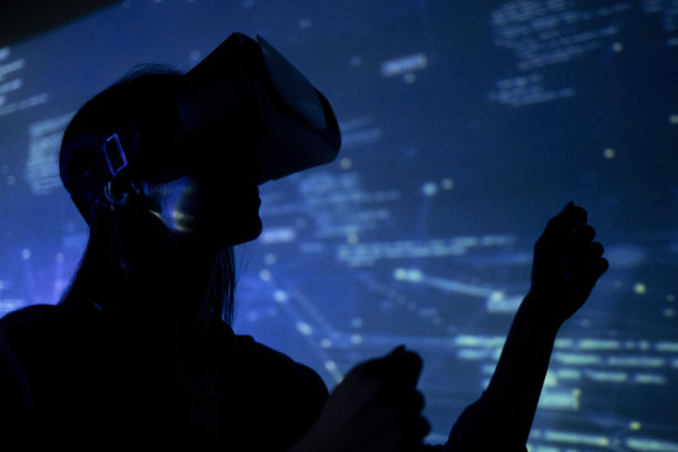 一名年轻女子戴着VR眼镜在黑暗的房间里看动画的照片图片下载