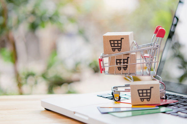 网上购物。信用卡和纸箱与购物车的标志在手推车上的笔记本电脑键盘。网上购物服务。提供送货上门服务图片下载