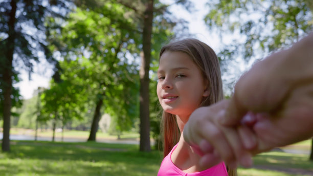 Pov拍摄的美丽的十几岁的女孩牵着朋友的手，看着相机在夏天的公园散步图片下载