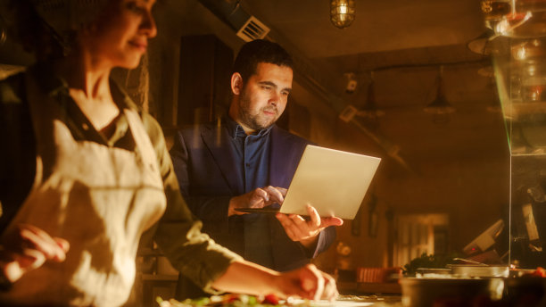 餐馆小企业主:男性和女性商业伙伴使用笔记本电脑。正宗的披萨店烹饪美味的有机生态食品。两个企业家在商店里进行网上订购图片下载