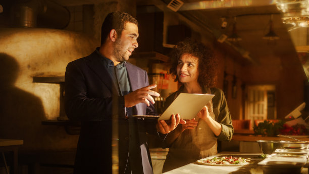 餐馆小企业主:快乐的男性和女性商业伙伴使用笔记本电脑，讨论增长战略。两名企业家致力于网店电子商务订单优化研究图片下载