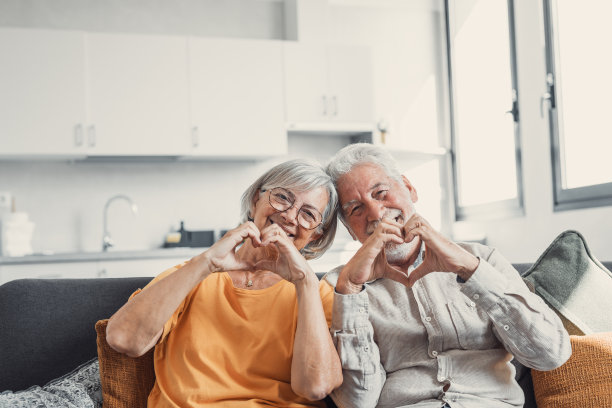 近距离特写幸福真诚的中年老年退休家庭夫妇在室内一起用手指做心形手势，表达爱意或表达真挚的感情，看着镜头。图片下载