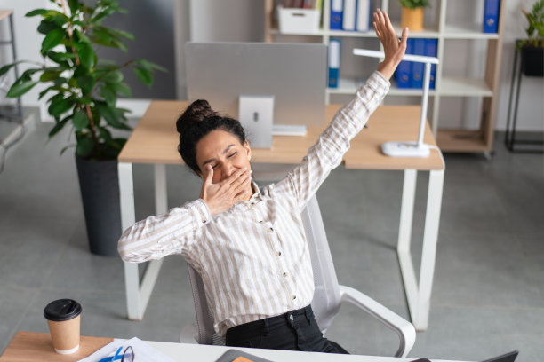 在办公室疲惫地伸着懒腰，感到困倦的年轻女商人图片下载