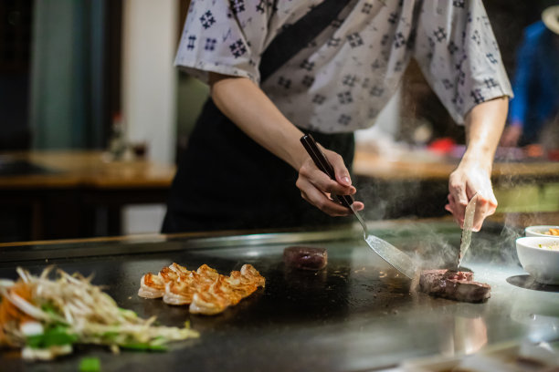 铁板烧——在平底锅上烤牛肉。厨师在热腾腾的餐桌上做饭图片下载