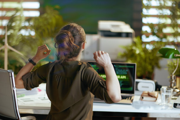 从后面看，一位拿着笔记本电脑的现代女性背部疼痛图片下载