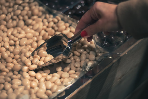 一位年轻女子在商店里用铲子拿起糖果。图片下载