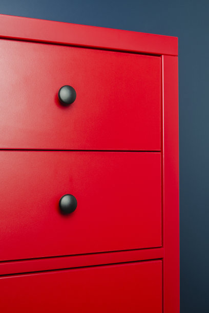 北欧风格的红色抽屉柜。一间公寓里有一个带黑色把手的红色木柜子图片下载
