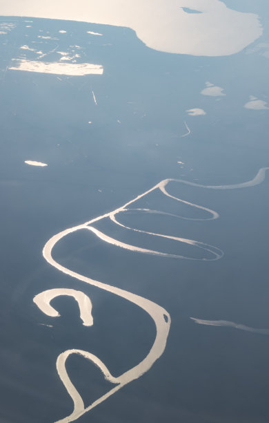 草原河流的鸟瞰图，映照着晴朗的天空，河流的线条穿过草原图片下载