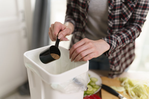 一名妇女在堆肥箱中倾倒发酵的博卡什。女性在家中堆肥有机食物垃圾。可持续生活方式概念图片下载