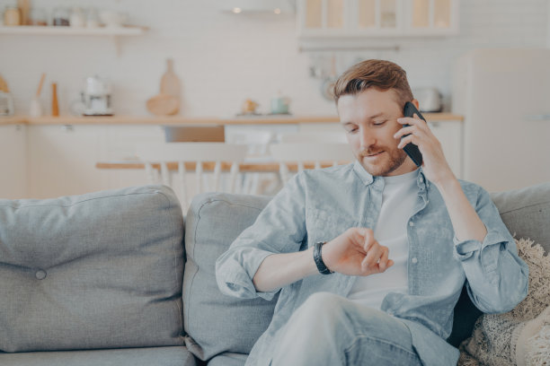 年轻人坐在沙发上和朋友打电话图片下载