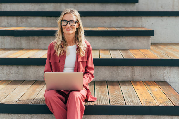 一个拿着笔记本电脑的女人坐在阳台上。图片下载