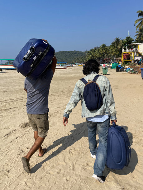 在印度海滩度假的男人提着行李箱的图像，度假照片，沙滩上有蓝天和树木在阳光明媚的一天在海滩度假图片下载