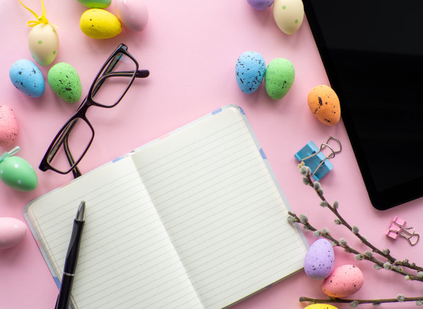 工作桌上的设备和复活节彩色鸡蛋在粉红色的背景图片下载
