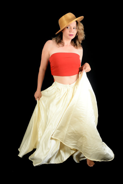 金发女孩穿着长裙，戴着帽子，金色微笑，黑色背景下的时尚照片。图片下载