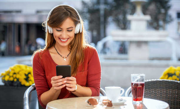 在线视频交流。年轻女子坐在咖啡馆里，用手机视频通话与朋友交流。生活方式、技术图片下载
