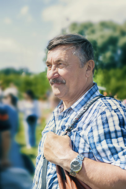 白发苍苍的老人站在城市街道前。一位70岁的老人微笑着图片下载