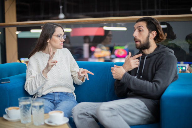 两个年轻的朋友坐在咖啡馆里用手语交谈。图片下载