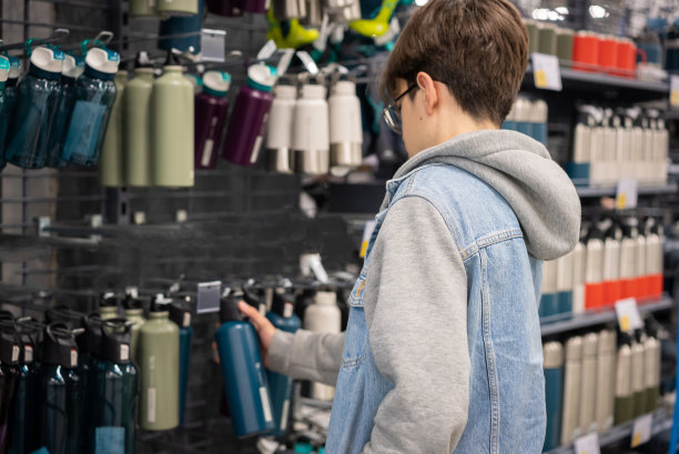 年轻的学校男孩从体育商店选择钢水瓶热图片下载