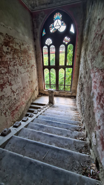 垂直拍摄了一座城堡里的旧彩色玻璃窗和楼梯图片下载