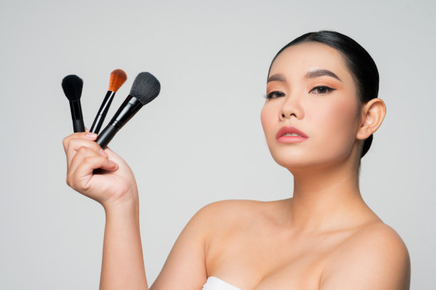美丽的亚洲女人肖像手持化妆腮红刷图片下载