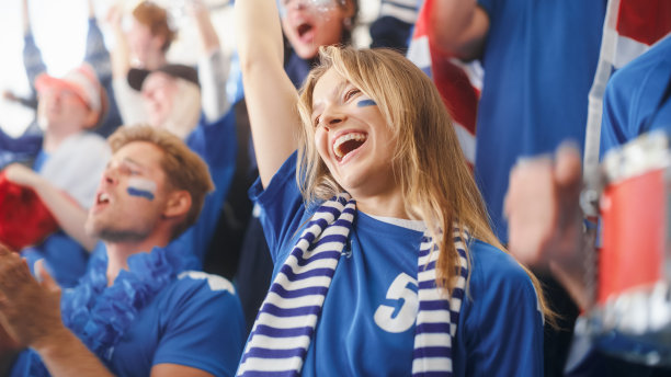 体育场馆大事件:美丽的助威女孩。一群脸上涂满彩绘的球迷为他们的蓝色足球队欢呼、呐喊。人们庆祝进球，冠军图片下载
