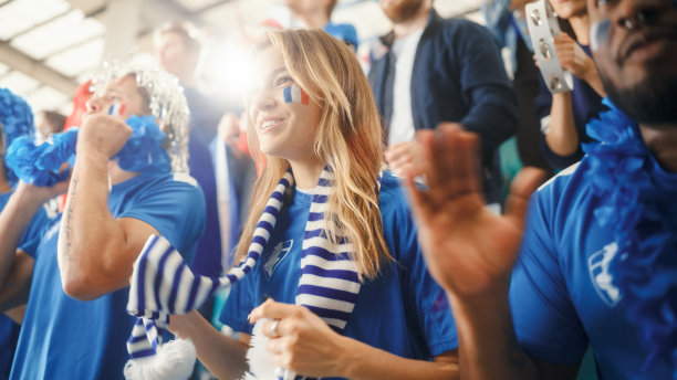 体育场足球赛:美丽的白人球迷女孩的肖像，脸上画着法国国旗，为她的球队加油。球迷欢呼，庆祝进球，冠军图片下载