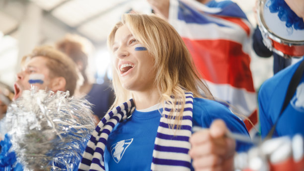 体育场馆大事件:美丽的助威女孩。一群脸上涂满彩绘的球迷为他们的蓝色足球队欢呼、呐喊。人们庆祝进球，冠军图片下载