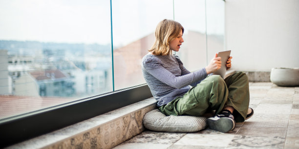 社交媒体影响力女孩坐在露台地板上使用笔记本电脑图片下载