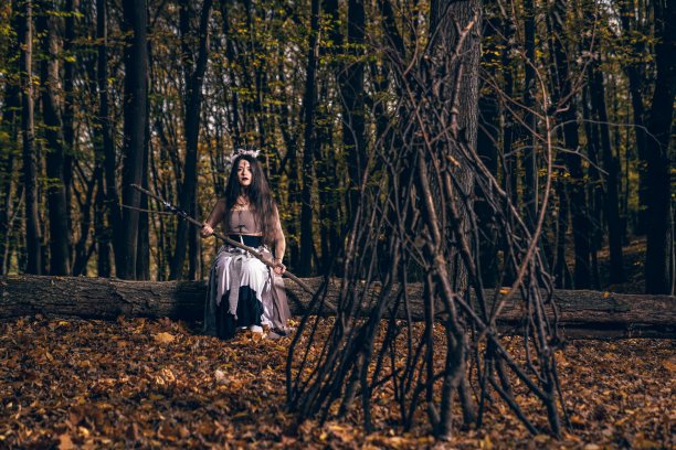 一头长发，脸上涂着女巫服装的年轻女子在森林里施咒图片下载
