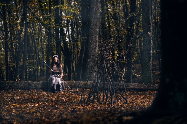 一头长发，脸上涂着女巫服装的年轻女子在森林里施咒图片下载