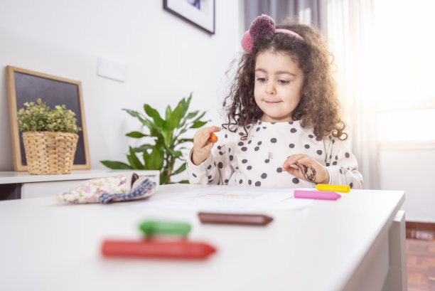 一个白人小女孩用彩色蜡笔画画的浅焦镜头图片下载