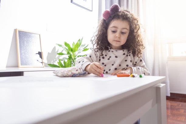 一个白人小女孩用彩色蜡笔画画的浅焦镜头图片下载