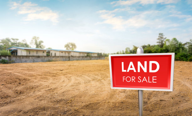 以修剪过的草坪为背景的土地出售标志。空旷的干裂沼泽复垦土，农村住房建设用地，美丽的蓝天。图片下载