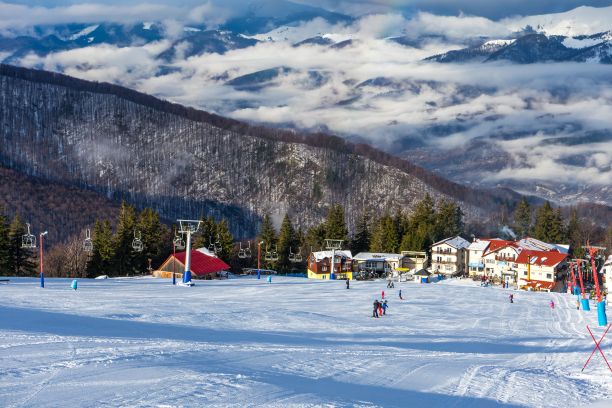 在蔚蓝多云的天空下，在山上乘坐缆车，欣赏冬季度假胜地的美景图片下载