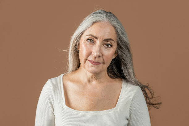 快乐漂亮的老年欧洲女士与自然的美丽，裸妆，灰色的头发看着相机图片下载