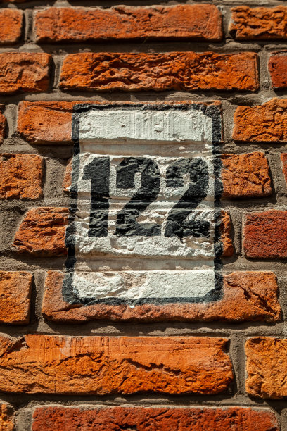 122数字装饰字体在黑色油漆对白色油漆盾牌手绘在房子的墙壁红砖。图片下载