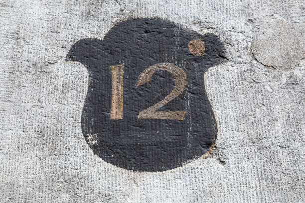 12个数字装饰字体在褪色的金色对黑色油漆盾牌手绘在房子的墙上。图片下载