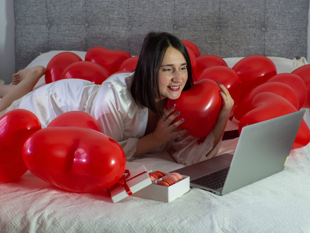 一名女子躺在床上，带着红色气球参加情人节派对图片下载