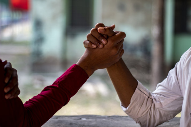 两个年轻人在摔跤，一个年轻人穿着红色衬衫，另一个年轻人穿着白色衬衫图片下载