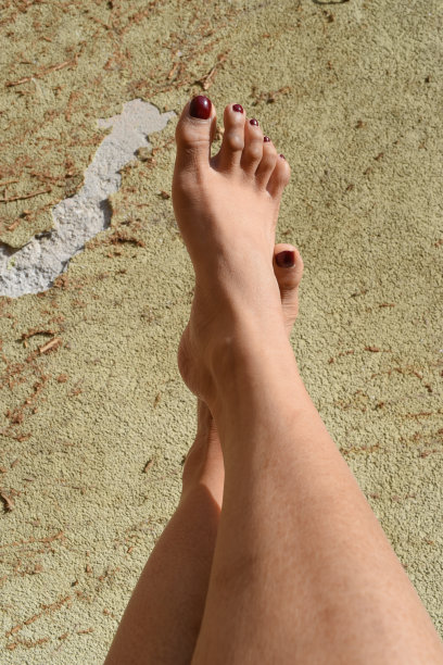 一对女性的腿靠在粗糙的水泥墙上图片下载