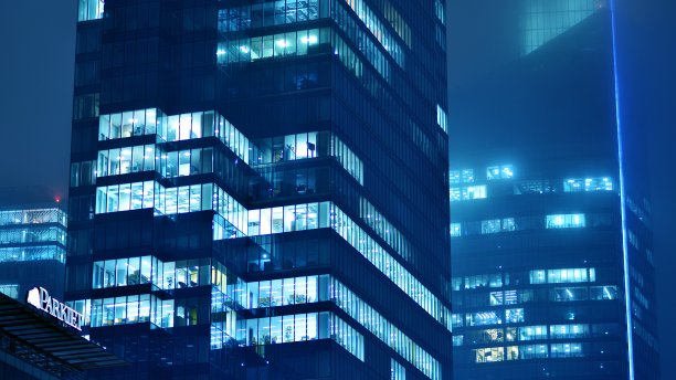 图案的办公楼窗户在夜间照明。图片下载
