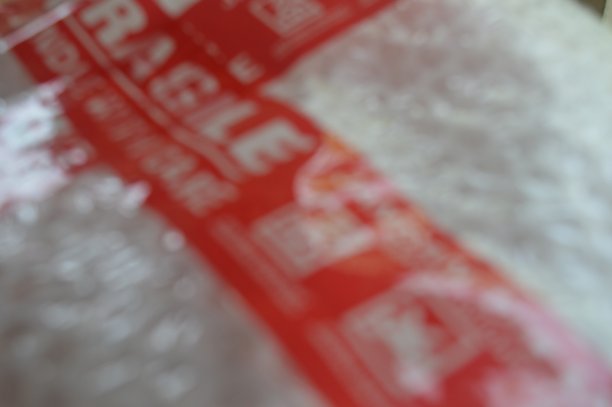 包裹在白色气泡膜和易碎胶带中的货物的散焦背景图片下载