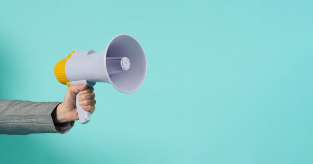 手握扩音器，穿着薄荷绿或蒂芙尼蓝背景的灰色西装。图片下载