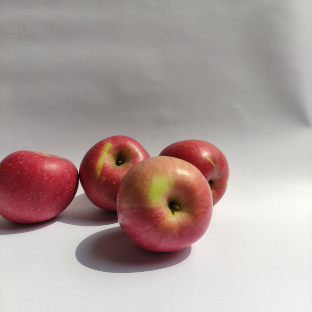 一些新鲜的红苹果在白色的草地上。图片下载