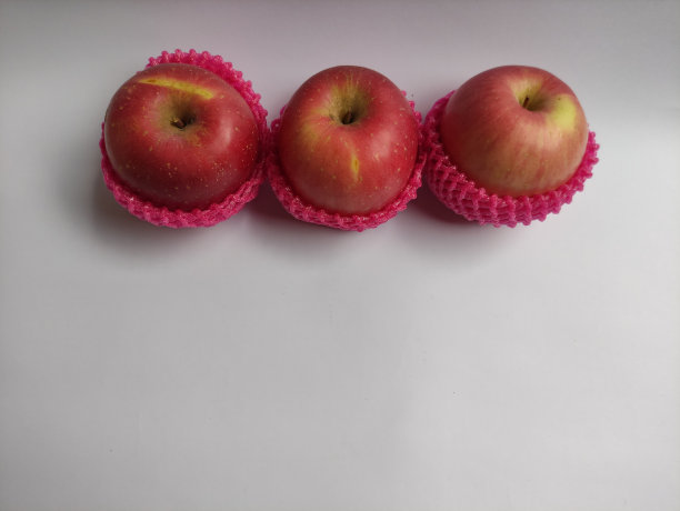 一些新鲜的红苹果在白色的草地上。图片下载