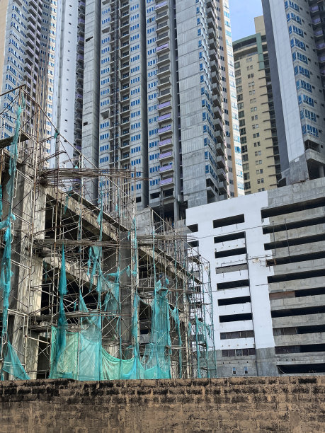 科伦坡市中心摩天大楼的全帧图像，建筑工地塔周围的脚手架杆和绿色网，新建筑，蓝天背景，低角度视图图片下载